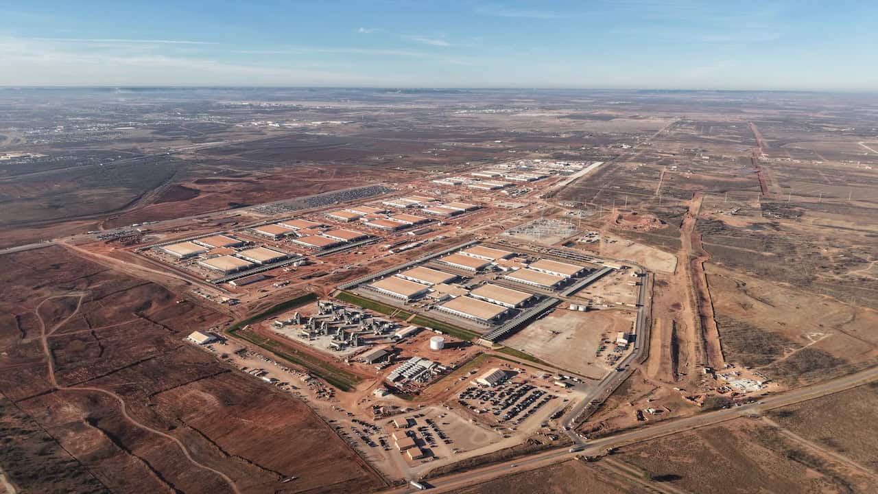 Aerial view of a large industrial complex with multiple buildings, surrounding infrastructure, and nearby construction by DPR Construction on a vast, mostly barren Texas landscape—ideal for hyperscale AI data centers.