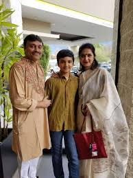 Three people stand together posing for a photo: Apurba Tribedi in a beige kurta, a boy in a brown shirt, and an adult woman in a white saree holding a red bag—capturing the spirit of Engineering for Impact.