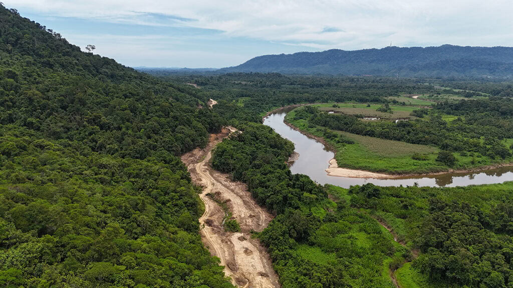 Aerial view of a river winding through a forested landscape in East Malaysia, with a deforested area along one bank and mountains in the background, featured in the YII Project Profile.