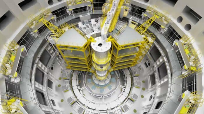 Inside view of the ITER (International Thermonuclear Experimental Reactor) assembly hall, showing complex machinery and yellow scaffolding structures for tokamak construction.