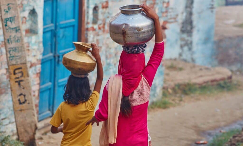 Two women carrying jars on their head in Uttar Pradesh, India.