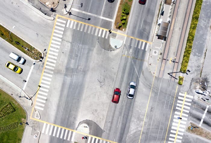 Aerial view of junction with traffic and pedestrians in the crosswalk.