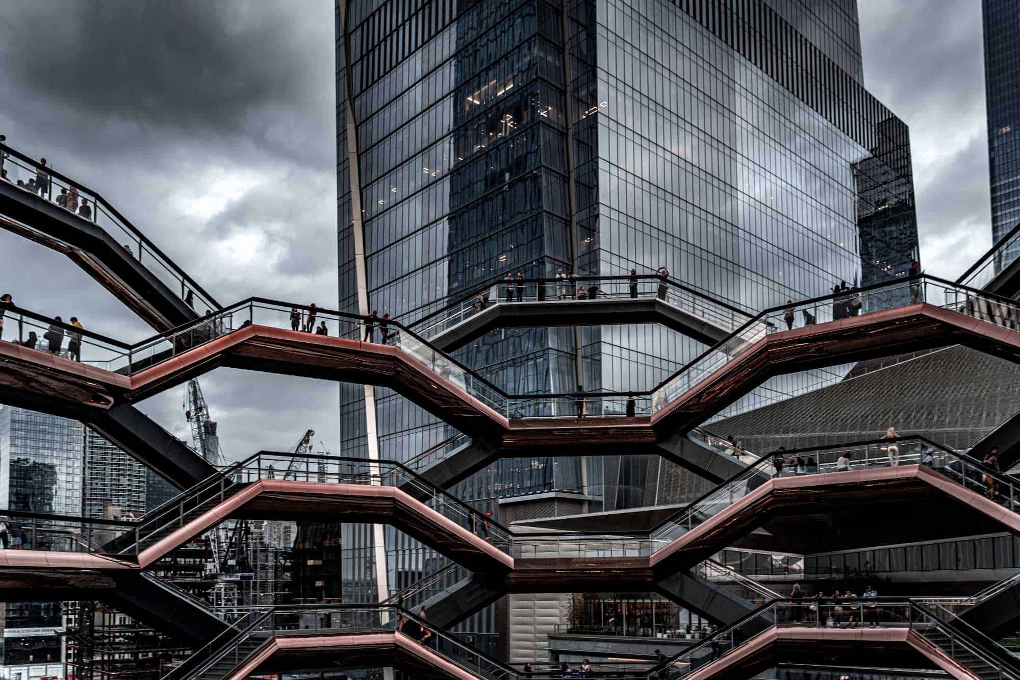 An overcast day at a modern urban structure with intersecting staircases and reflective buildings.