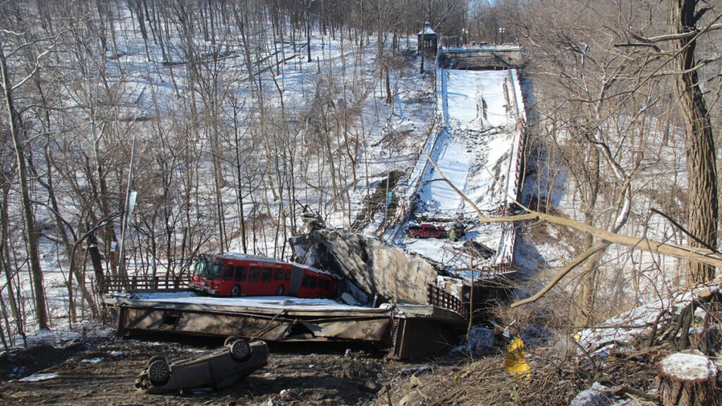 Collapsed snow-covered bridge in a wooded area highlights the U.S. Bridge Crisis, with a red bus and car on the wreckage and an overturned car below.