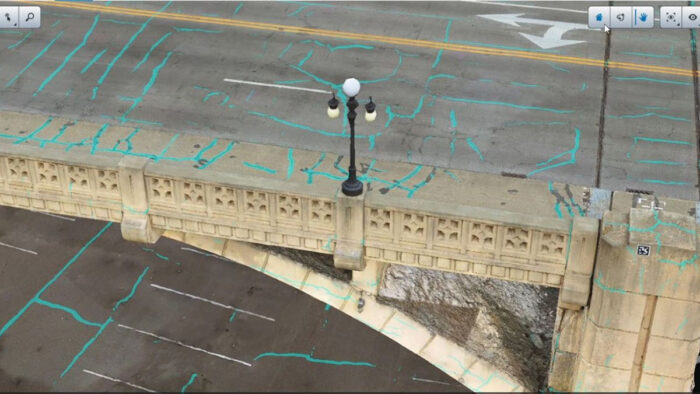 Aerial view of a bridge with a lamp post, road markings, and blue survey lines across the structure—ideal for Digital Twins modeling and AI analysis in addressing the U.S. Bridge Crisis.