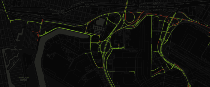 A map displaying routes highlighted in green and red overlays on a dark background, indicating traffic flow and road layout in an urban area.