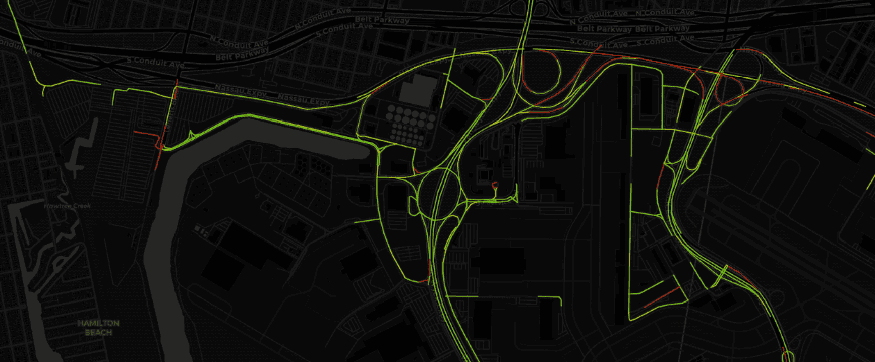 A map displaying routes highlighted in green and red overlays on a dark background, indicating traffic flow and road layout in an urban area.