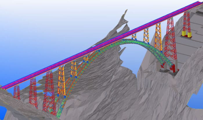 A colorful, computer-generated 3D model of a large arched bridge spanning a rocky gorge. The bridge features red, green, and blue structural elements with tall support towers.