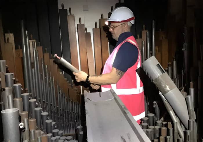 construction worker with hardhat looking at pipe organ parts