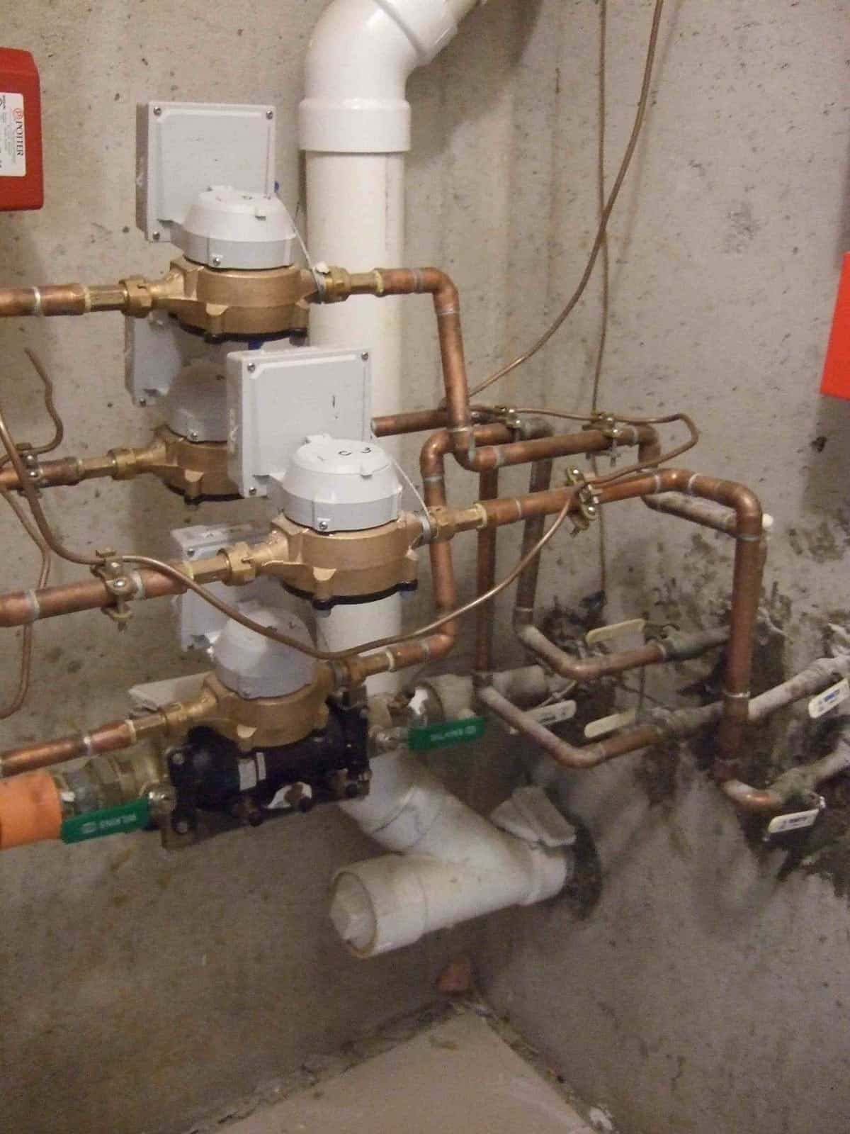 Complex network of pipes and valves for drinking water in a utility room.