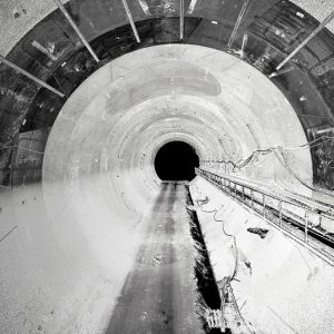 Black and white image showing the interior of a large, circular tunnel with cables running along the right side—an impressive project by Italferr S.p.A.; a gray badge at left reads “B Winner 2025.”.