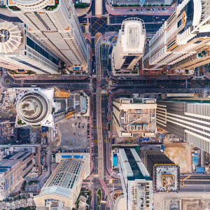 Aerial view of a city intersection with tall skyscrapers, busy roads, and a marina with boats