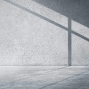 A minimalist interior with concrete walls and floor, featuring shadows cast by an unseen window. A minimalist interior with concrete walls and floor, featuring shadows cast by an unseen window.