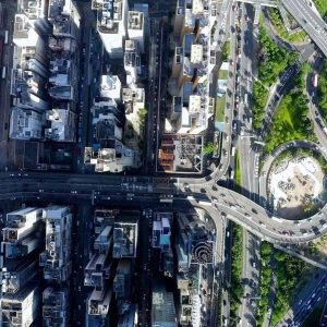 Aerial view of a city with tall buildings, intersecting highways, a circular roundabout, and green spaces visible among the roads—ideal for optimizing CAD workflows with MicroStation 2025.