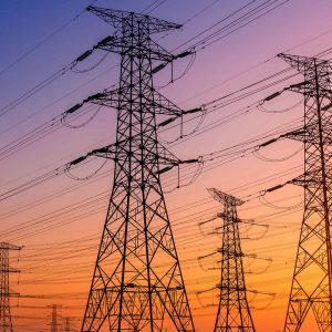Silhouettes of transmission towers against a vibrant sunset sky.