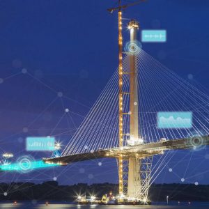 A large cable-stayed bridge under construction at night, illuminated by lights, with digital network graphics overlaid—showcasing the power of infrastructure digital twin technology.