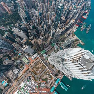 Aerial view of densely packed skyscrapers and waterfront in a modern city with turquoise water and boats highlights impressive infrastructure engineering.
