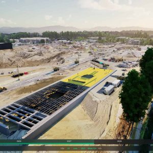 A large construction site with a partially built structure in the center, surrounded by machinery, equipment, and cleared land under a partly cloudy sky—showcasing modern design and the use of digital twins in construction.
