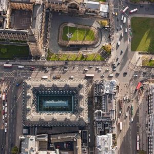 Aerial view of a busy city intersection in London, where smart mobility integrates roads, vehicles, green spaces, and historic buildings like the Palace of Westminster—highlighting the evolution of modern cities.