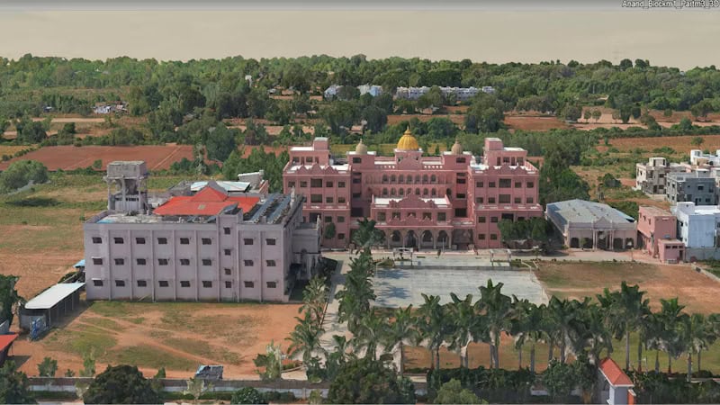 Aerial view of a large pink building with a yellow dome, surrounded by trees, smaller buildings, and an open courtyard—an iconic architectural feature often found in India. This striking scene provides valuable context for geospatial data and city-scale data management applications.