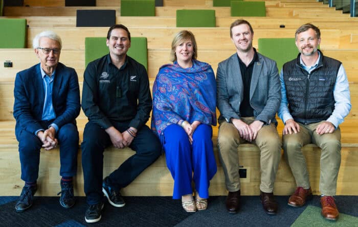 Five people sitting on wooden steps, smiling for a group photo.