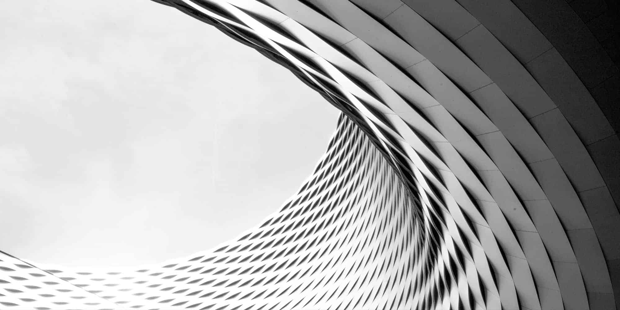Monochrome architectural detail showcasing a curved facade with repetitive geometric patterns.