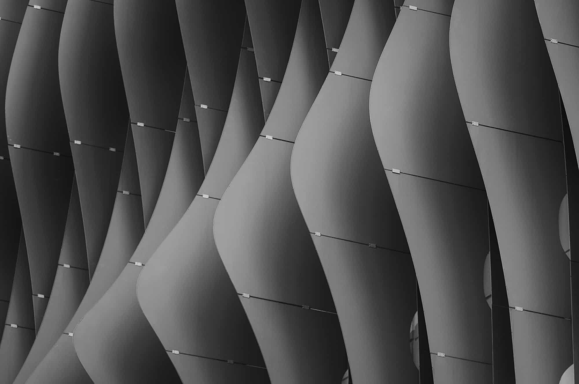 Repetitive curved metal panels in a monochromatic pattern.