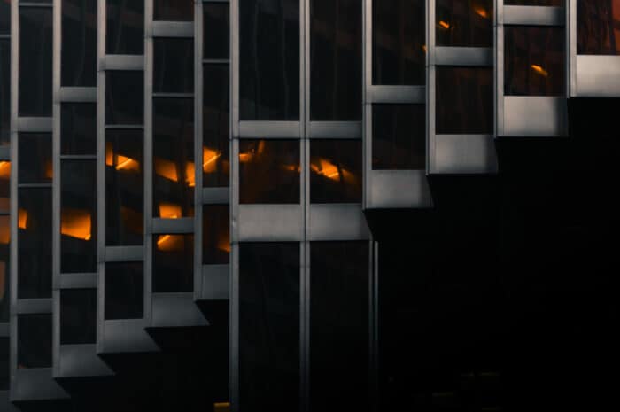 Abstract view of a modern building with geometric patterns and warm lights visible from within.