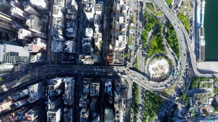 Aerial view of a city with tall buildings, intersecting highways, a circular roundabout, and green spaces visible among the roads—ideal for optimizing CAD workflows with MicroStation 2025.