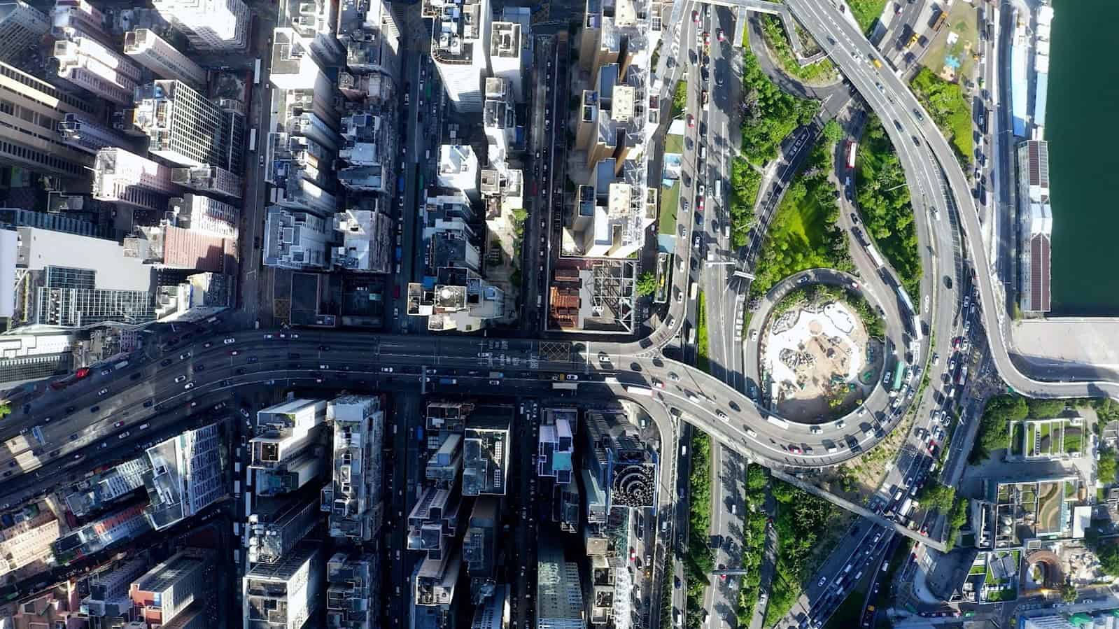Aerial view of a city with tall buildings, intersecting highways, a circular roundabout, and green spaces visible among the roads—ideal for optimizing CAD workflows with MicroStation 2025.