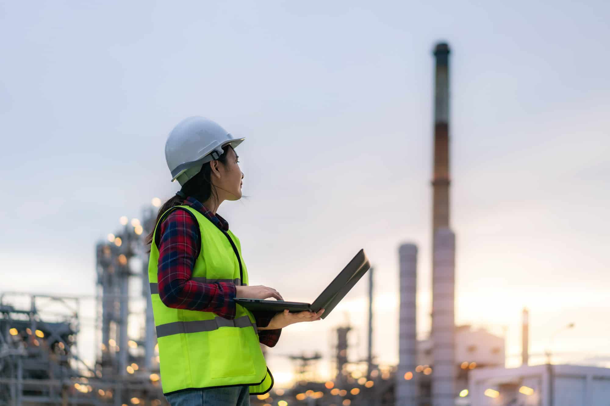woman with hard hat on in front of infrastructure plant