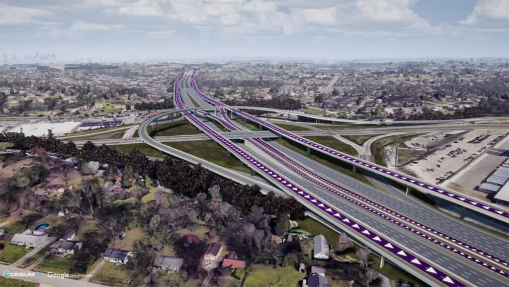 Aerial view of a large highway interchange with multiple lanes and overpasses, surrounded by residential neighborhoods and light industrial areas.