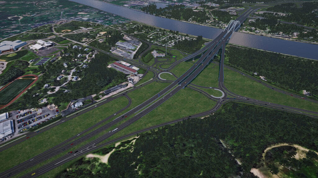 Aerial view of a large highway interchange with multiple overpasses and ramps crossing a river, surrounded by greenery, buildings, and a parking lot.