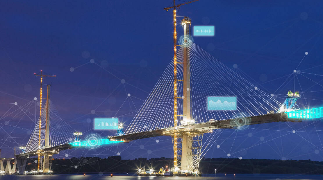 A large cable-stayed bridge under construction at night, illuminated by lights, with digital network graphics overlaid—showcasing the power of infrastructure digital twin technology.