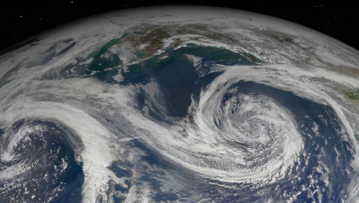 A satellite image of Earth showing swirling cloud patterns over a large body of water, with landmasses partially visible at the top of the image.