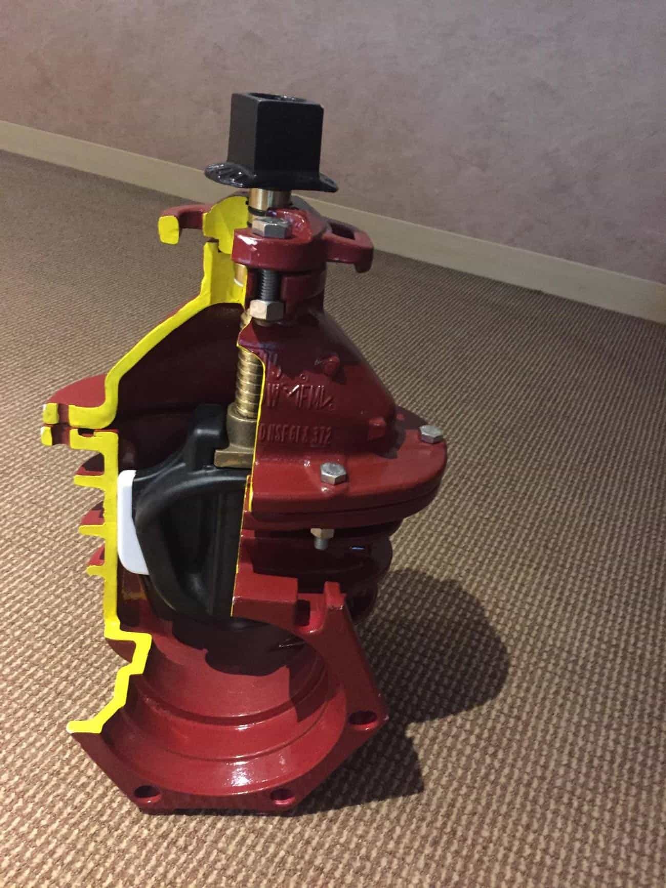 Red and yellow standalone fire hose valve installed on a carpeted floor