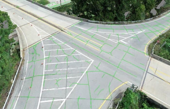 Aerial view of an intersection with road markings and surrounding greenery.