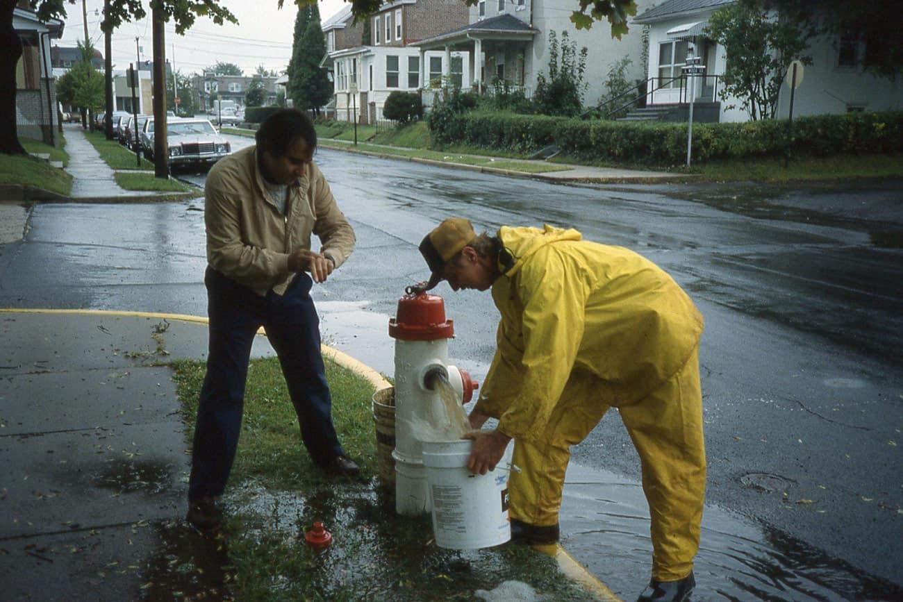 two men working on a fire hydrant in a neighborhood