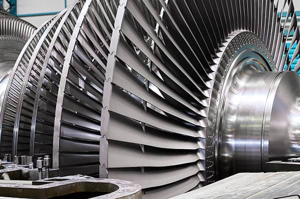 Close-up view of large metallic turbine blades and rotor components inside an industrial facility, showcasing Nippoh Engineering’s commitment to carbon-neutral design for a sustainable future.