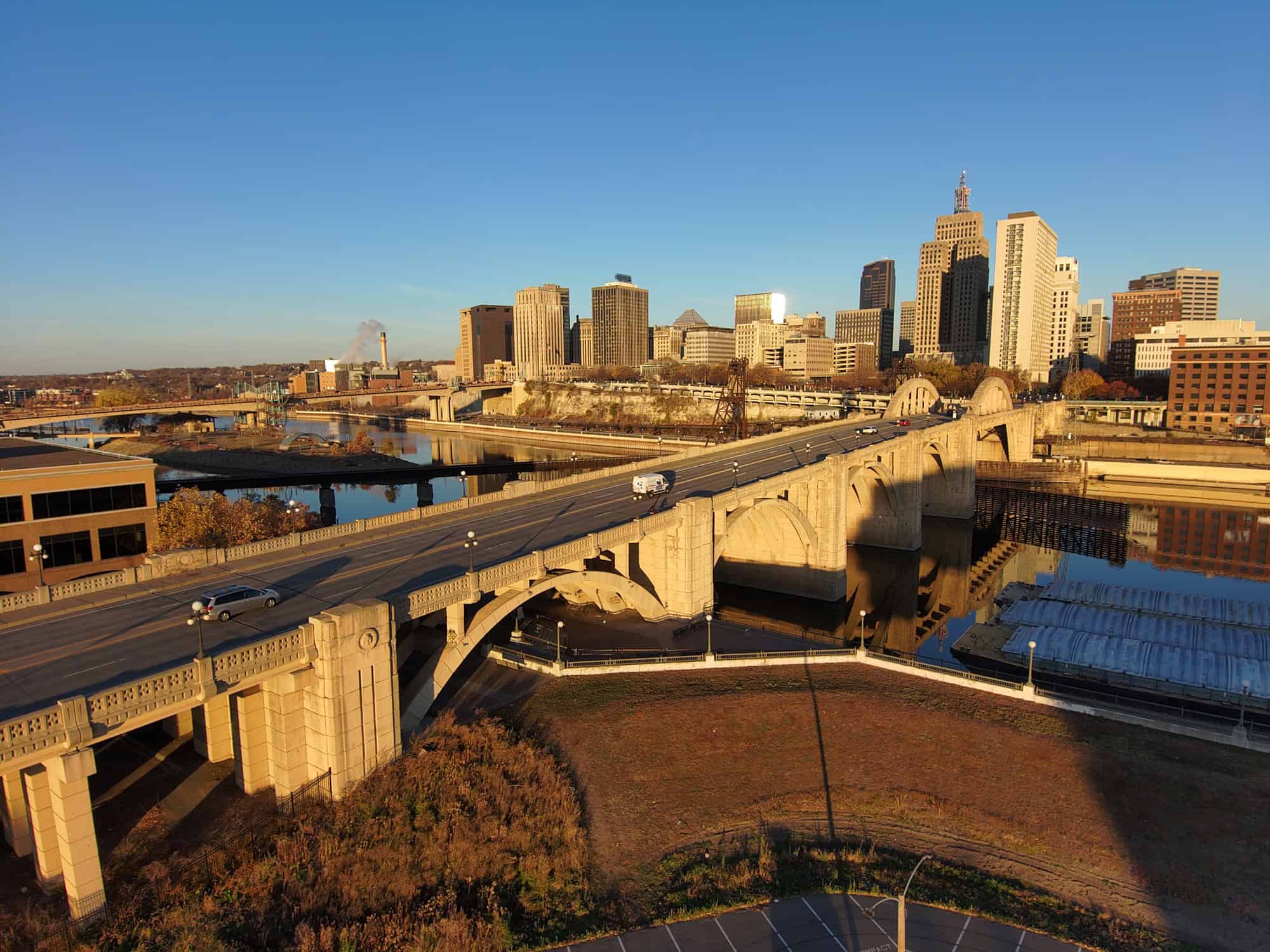 Aerial view of vehicles crossing the Robert Street Bridge, set against a backdrop of skyscrapers under a clear blue sky in St. Paul, Minnesota.
