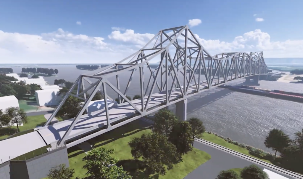 A large steel truss bridge, showcasing innovative bridge design, spans across a wide river surrounded by trees and grassy areas under a partly cloudy blue sky.