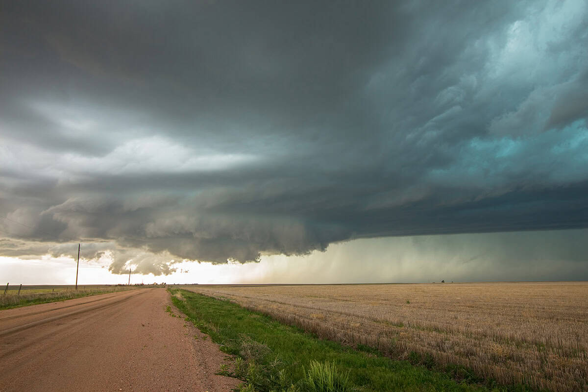 A large, dark storm cloud looms over a rural dirt road and open fields, with rain visible in the distance—evoking the visualization challenges faced before innovative solutions like iTwin Engage.