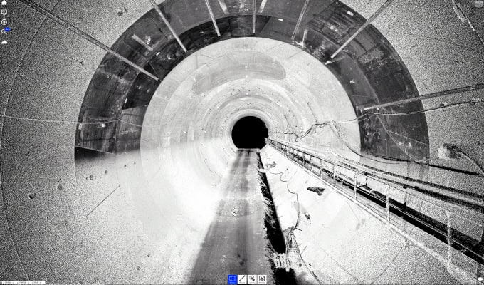 A grayscale image of the Serravalle Tunnel, with cables running along the right wall, receding into darkness at the far end—an ideal setting for AI-Powered Digital Twin technology by Italferr.