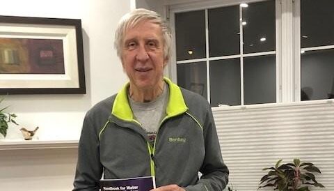 Tom Walski standing and holding a book