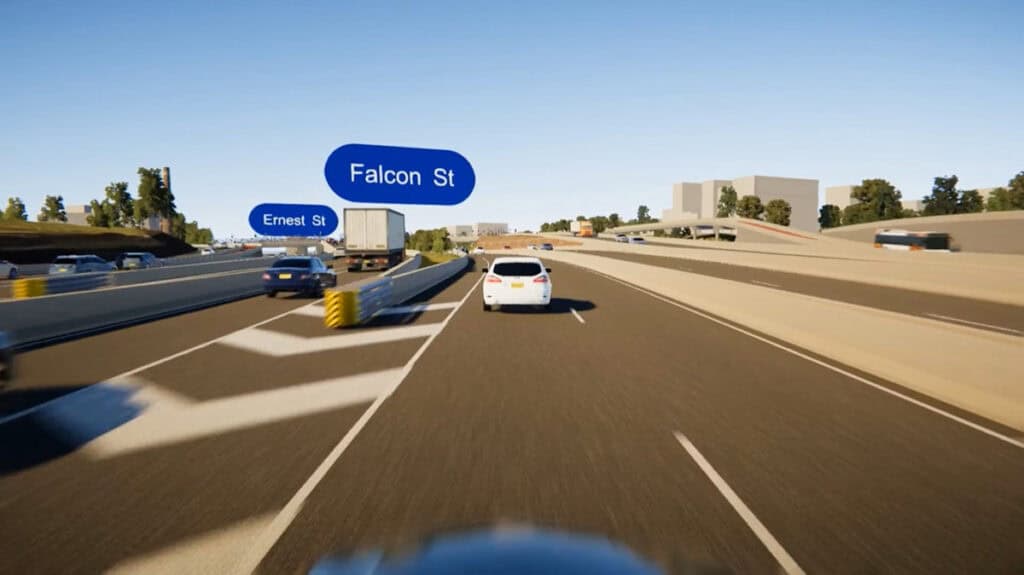 A highway scene on the Warringah Freeway shows several cars driving; blue road signs label "Falcon St" and "Ernest St" above two exits. Urban freeways and city buildings, along with trees, are visible in the background.