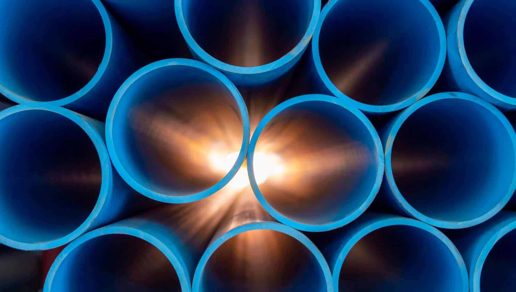 A model bundle of blue PVC pipes with light shining through the central conduit, designed for solving water pressure problems.