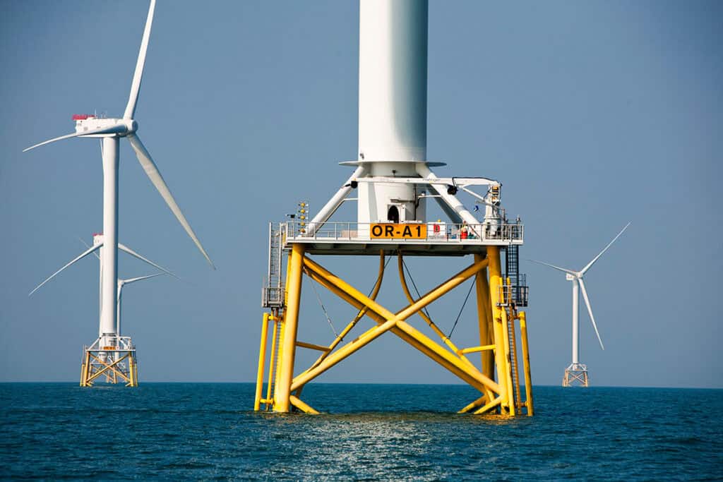 Offshore wind turbines stand in the ocean under clear skies, harnessing offshore wind energy. In the foreground, PLAXIS and SACS support geotechnical modelling, with additional turbine structures visible in the distance.