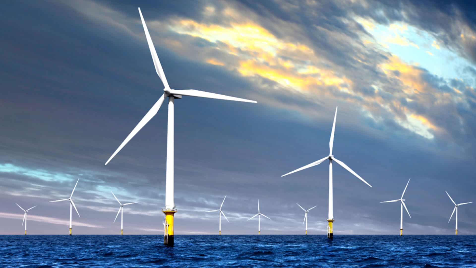 Offshore wind turbines, showcasing cutting-edge wind turbine design, stand majestically in a body of water beneath a cloudy sky at sunset.